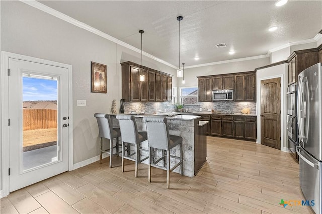 kitchen featuring stainless steel appliances, dark brown cabinets, a peninsula, and decorative backsplash