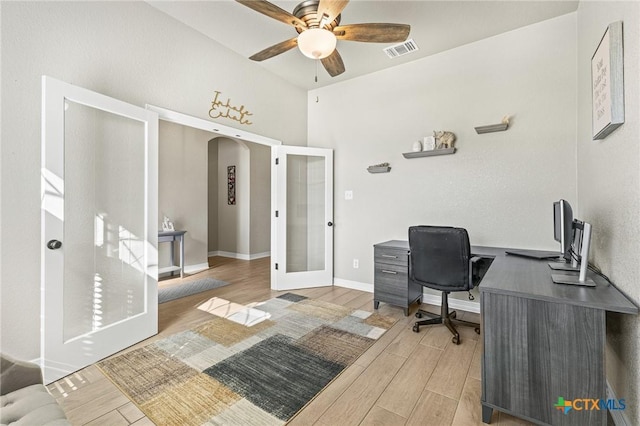 office space featuring arched walkways, wood finished floors, visible vents, a ceiling fan, and french doors