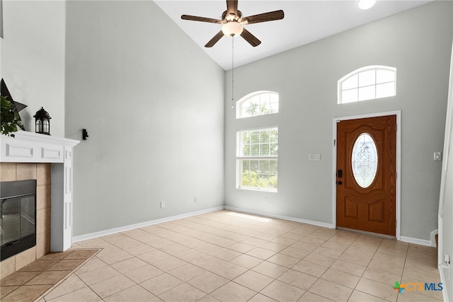 foyer entrance featuring a wealth of natural light, light tile patterned floors, a fireplace, and high vaulted ceiling