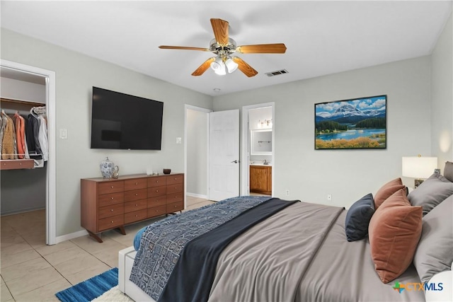 tiled bedroom featuring a walk in closet, connected bathroom, a closet, and ceiling fan