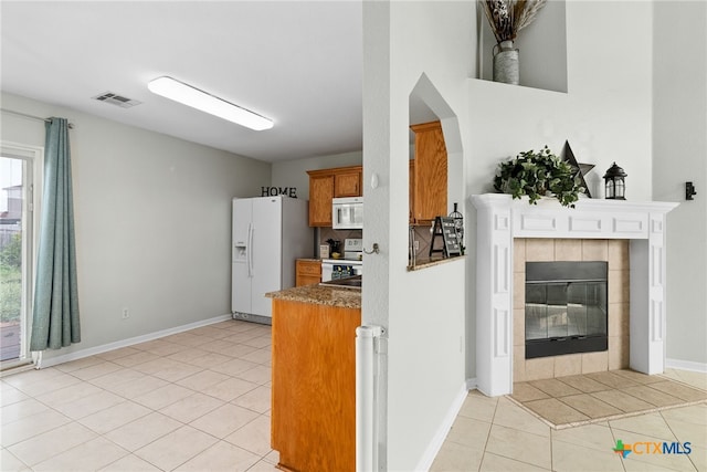 kitchen featuring white appliances, a fireplace, and light tile patterned floors