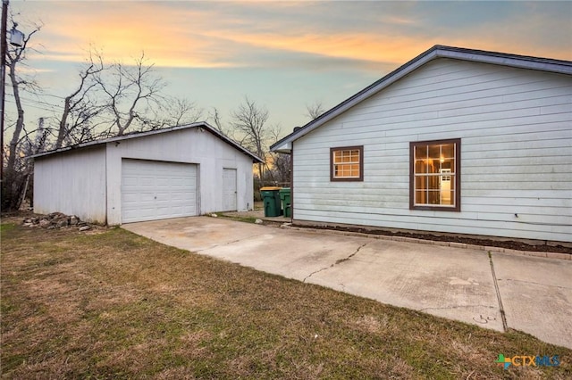 property exterior at dusk with an outbuilding, a garage, and a lawn