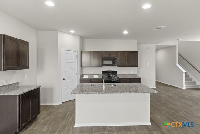 164 Linnet Ln, Maxwell, TX 78656 - kitchen with black microwave, range, light stone counters, dark brown cabinetry, and recessed lighting