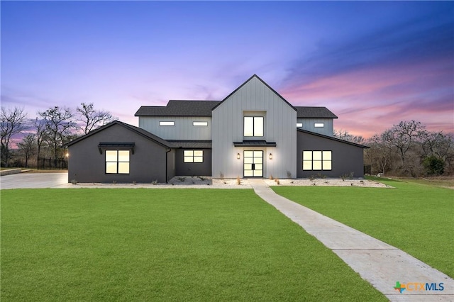 modern farmhouse style home featuring roof with shingles, a lawn, and board and batten siding