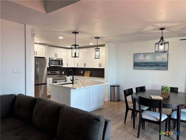 kitchen with tasteful backsplash, light wood-style flooring, open floor plan, stainless steel appliances, and white cabinetry