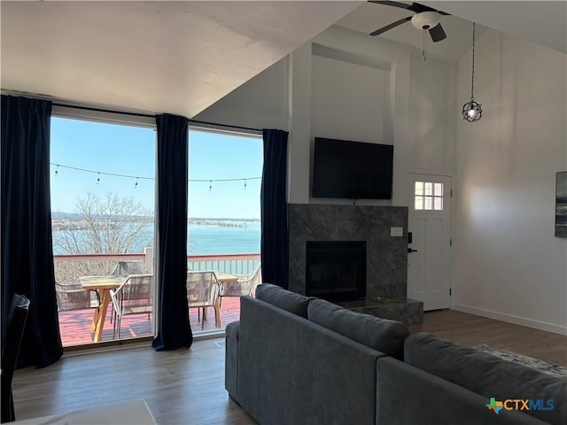 living room with ceiling fan, wood finished floors, a high end fireplace, and baseboards