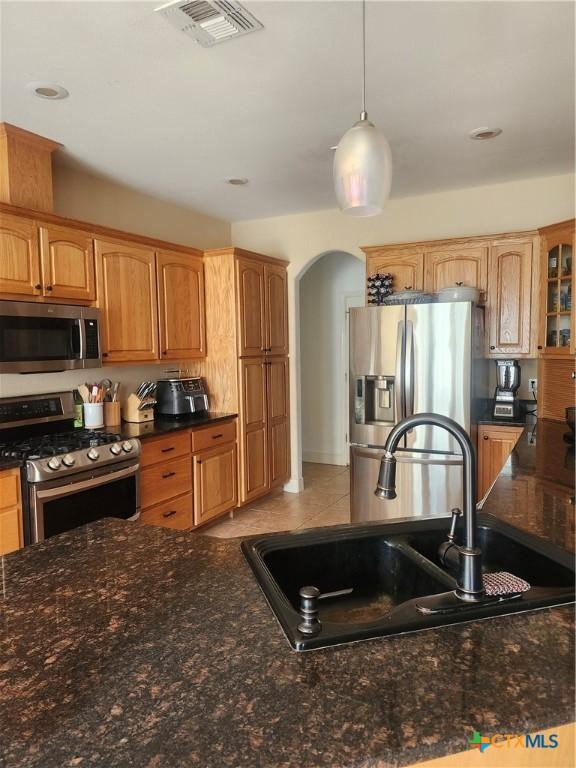 56 Post Oak Jct, Inez, TX 77968 - kitchen with stainless steel appliances, a sink, arched walkways, pendant lighting, and dark stone counters