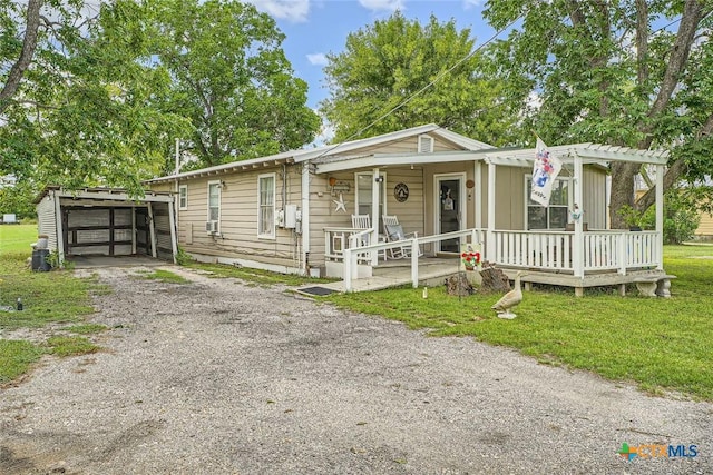 1309 Blackjack St, Lockhart, TX 78644 - view of front facade with driveway, covered porch, a front lawn, and an outbuilding