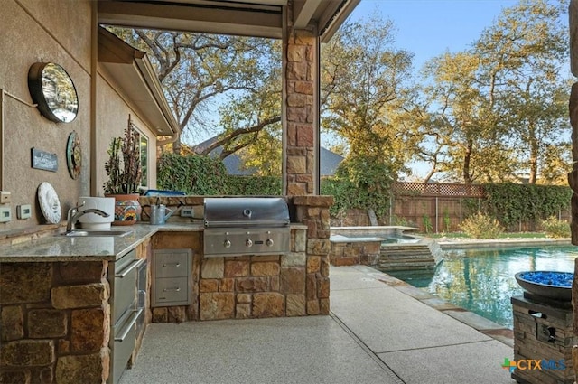 view of patio / terrace featuring a pool with hot tub, sink, a grill, and an outdoor kitchen