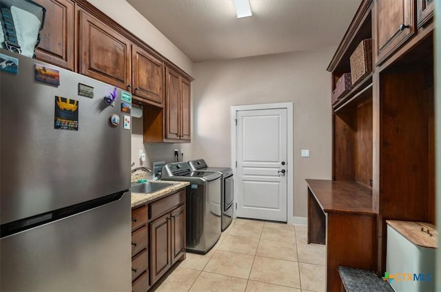 clothes washing area featuring light tile patterned floors, sink, independent washer and dryer, and cabinets