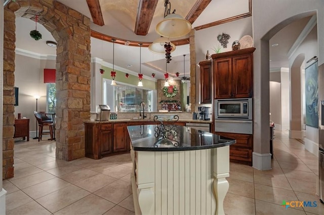 kitchen with light tile patterned floors, stainless steel microwave, sink, pendant lighting, and a center island