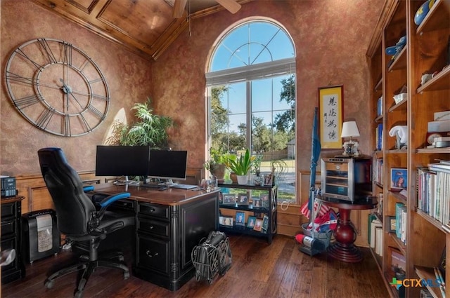 office area with beam ceiling, dark wood-type flooring, crown molding, and a towering ceiling