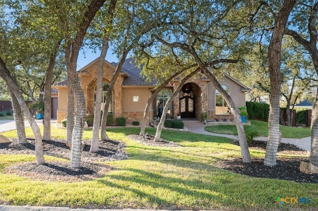 view of front facade featuring a front lawn, stone siding, and stucco siding