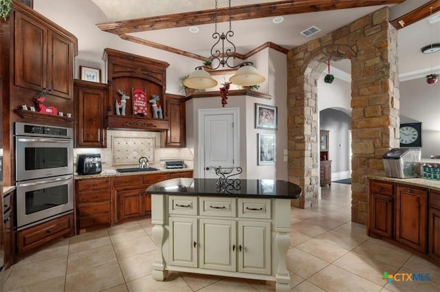 kitchen featuring stainless steel double oven, a kitchen island, decorative light fixtures, cooktop, and backsplash