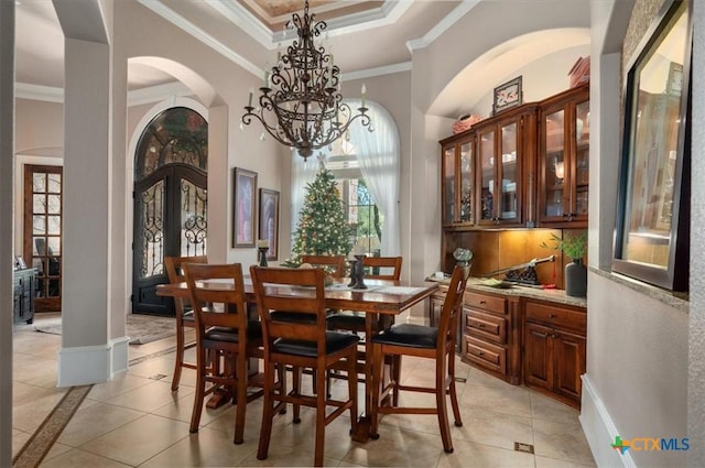 tiled dining space with french doors, a raised ceiling, crown molding, and a chandelier