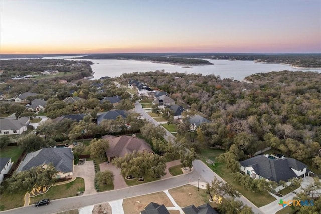 aerial view at dusk featuring a water view