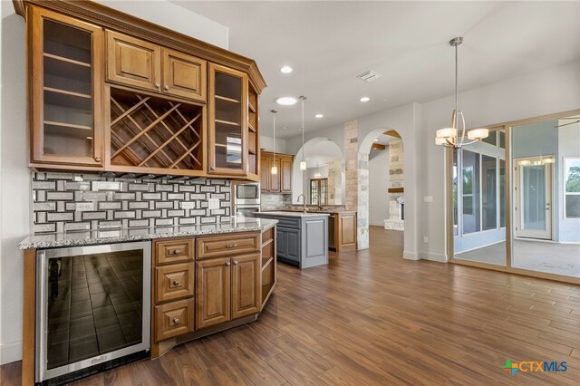 1607 Filtro, New Braunfels, TX 78132 - bar area with beverage cooler, arched walkways, dark wood-style floors, tasteful backsplash, and hanging light fixtures
