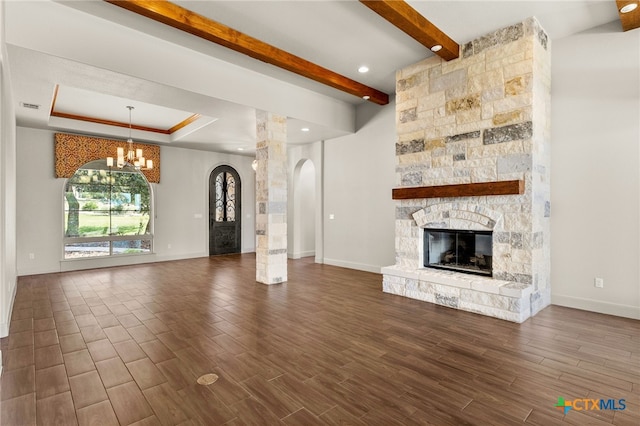 1607 Filtro, New Braunfels, TX 78132 - unfurnished living room with arched walkways, a chandelier, a stone fireplace, dark wood-style flooring, and ornate columns