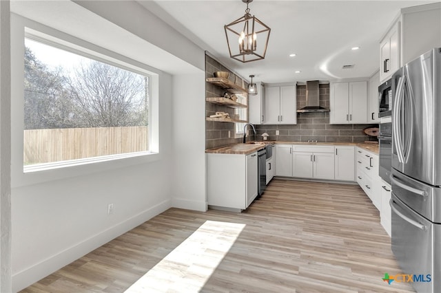 kitchen featuring open shelves, appliances with stainless steel finishes, wall chimney range hood, decorative backsplash, and a healthy amount of sunlight