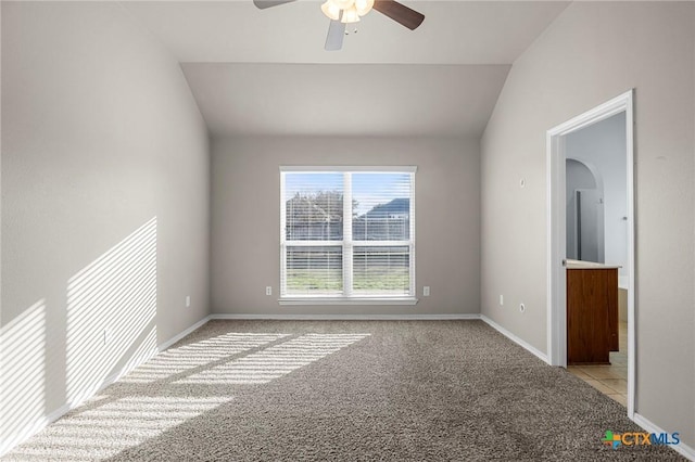 carpeted spare room featuring vaulted ceiling and ceiling fan