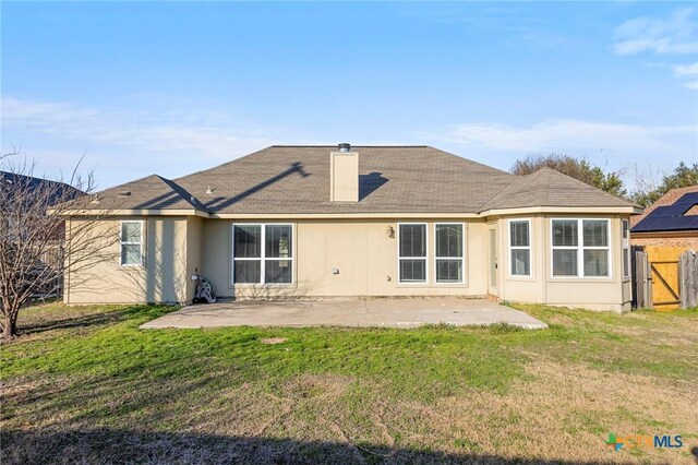 back of property featuring a lawn, a patio, and fence