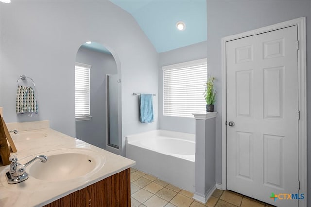 bathroom featuring tile patterned floors, a bath, vaulted ceiling, and vanity