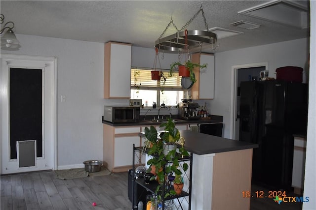 kitchen featuring black refrigerator with ice dispenser, white cabinets, sink, hardwood / wood-style flooring, and a textured ceiling