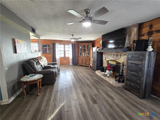 living room with hardwood / wood-style floors, a textured ceiling, a brick fireplace, and wooden walls