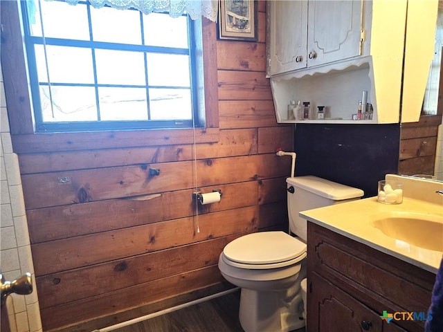 bathroom with hardwood / wood-style floors, vanity, toilet, and wooden walls