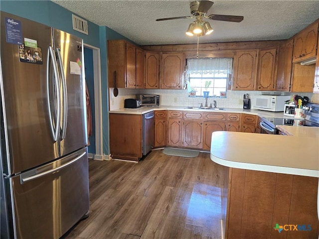 kitchen featuring a textured ceiling, sink, kitchen peninsula, and stainless steel appliances