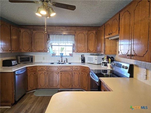 kitchen featuring sink, ceiling fan, a textured ceiling, dark hardwood / wood-style flooring, and stainless steel appliances