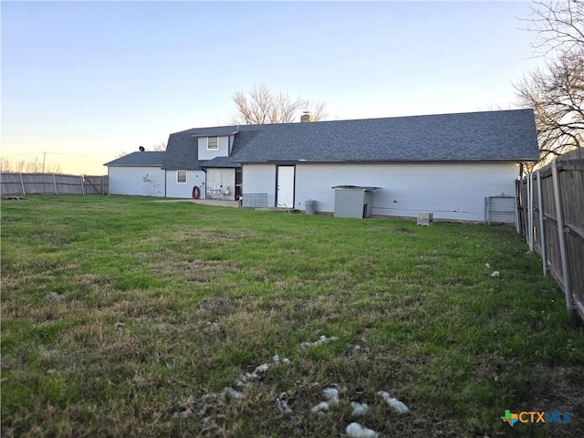 back house at dusk featuring a yard