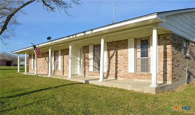 rear view of property featuring a lawn and brick siding