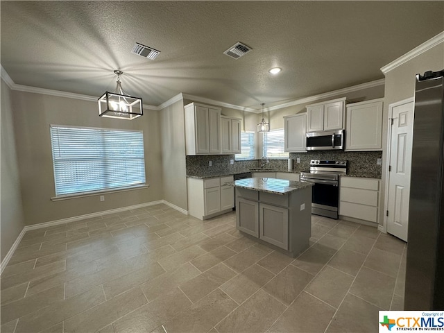 kitchen with stainless steel appliances, white cabinets, decorative light fixtures, and a center island