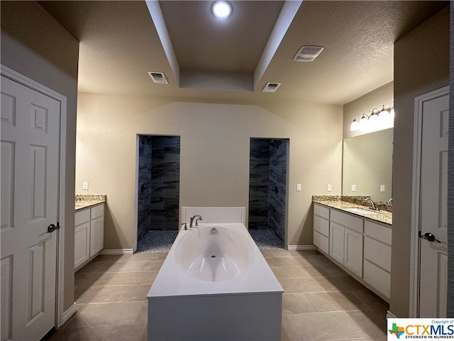 bathroom with tile patterned flooring, vanity, a textured ceiling, and a bath