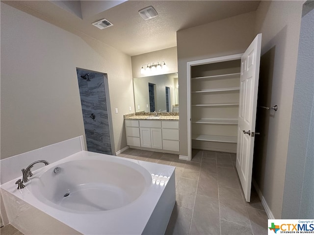 bathroom featuring vanity, a textured ceiling, tile patterned floors, and a bathtub