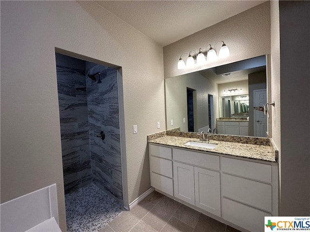 bathroom with tiled shower, vanity, a textured ceiling, and tile patterned floors