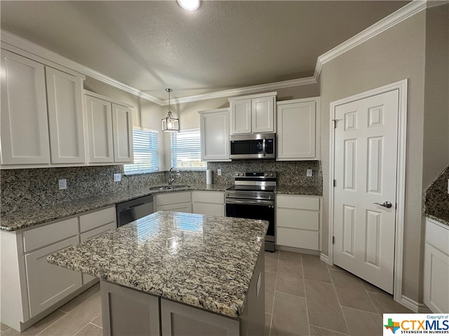 kitchen featuring a kitchen island, white cabinetry, appliances with stainless steel finishes, backsplash, and sink