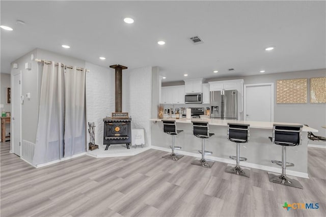 735 Slawson Ln, Killeen, TX 76542 - kitchen with appliances with stainless steel finishes, light wood-type flooring, a wood stove, light countertops, and recessed lighting