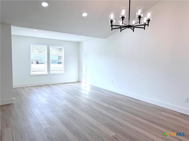 unfurnished dining area with recessed lighting, baseboards, wood finished floors, and a chandelier