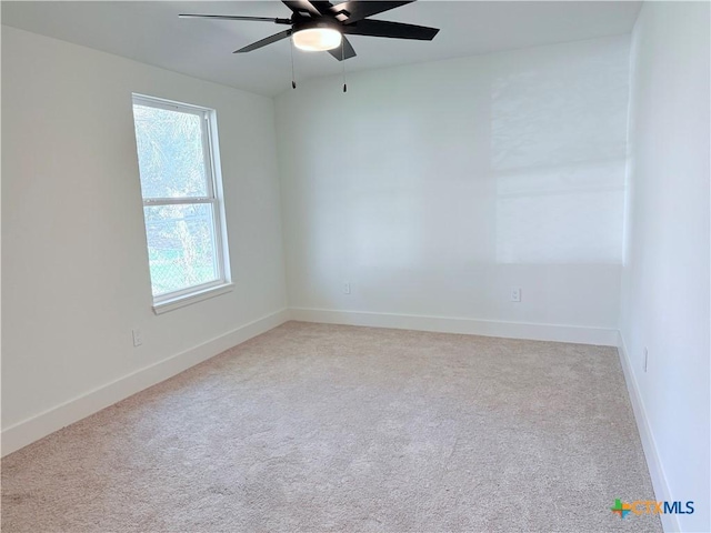 carpeted spare room featuring baseboards and a ceiling fan