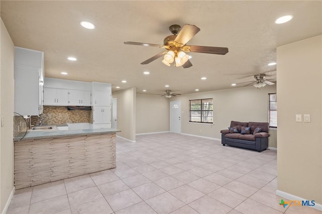 kitchen featuring sink, light tile patterned floors, kitchen peninsula, decorative backsplash, and white cabinets