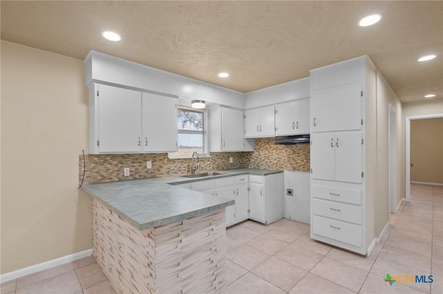 kitchen featuring sink, white cabinetry, tasteful backsplash, light tile patterned floors, and kitchen peninsula