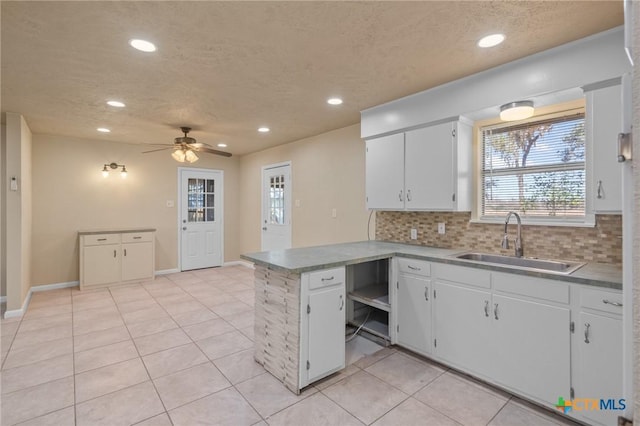 kitchen featuring white cabinetry, kitchen peninsula, sink, and decorative backsplash