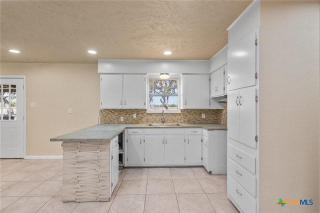 kitchen featuring white cabinetry, sink, tasteful backsplash, and kitchen peninsula