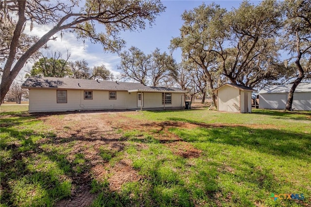 rear view of property featuring a yard and a storage shed