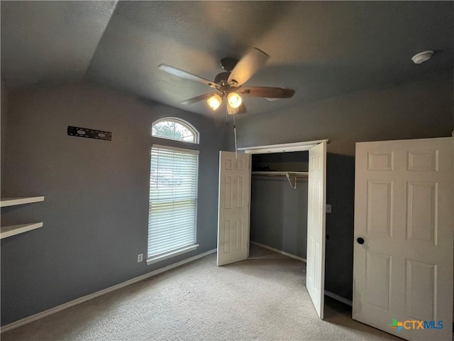 unfurnished bedroom with ceiling fan, baseboards, lofted ceiling, light carpet, and a closet