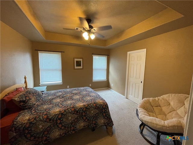 bedroom featuring baseboards, a raised ceiling, carpet, and ceiling fan