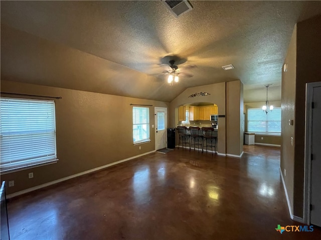 unfurnished living room featuring baseboards, concrete floors, vaulted ceiling, a textured ceiling, and ceiling fan with notable chandelier