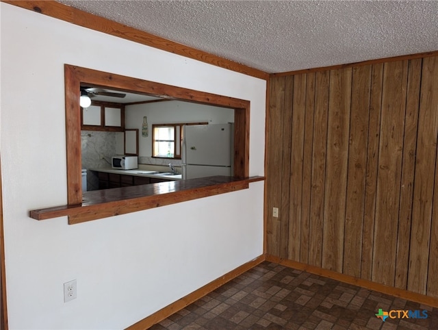 1201 Oblate Dr, Canyon Lake, TX 78133 - kitchen with white appliances, wood walls, baseboards, brick patterned floors, and a textured ceiling